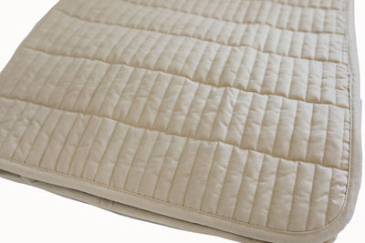 A tan quilted folded blanket on a white background.