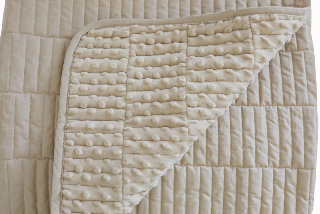 A dual sided cream blanket, one side velvet and one side minky