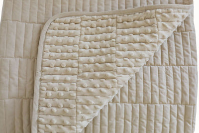 A dual sided cream blanket, one side velvet and one side minky