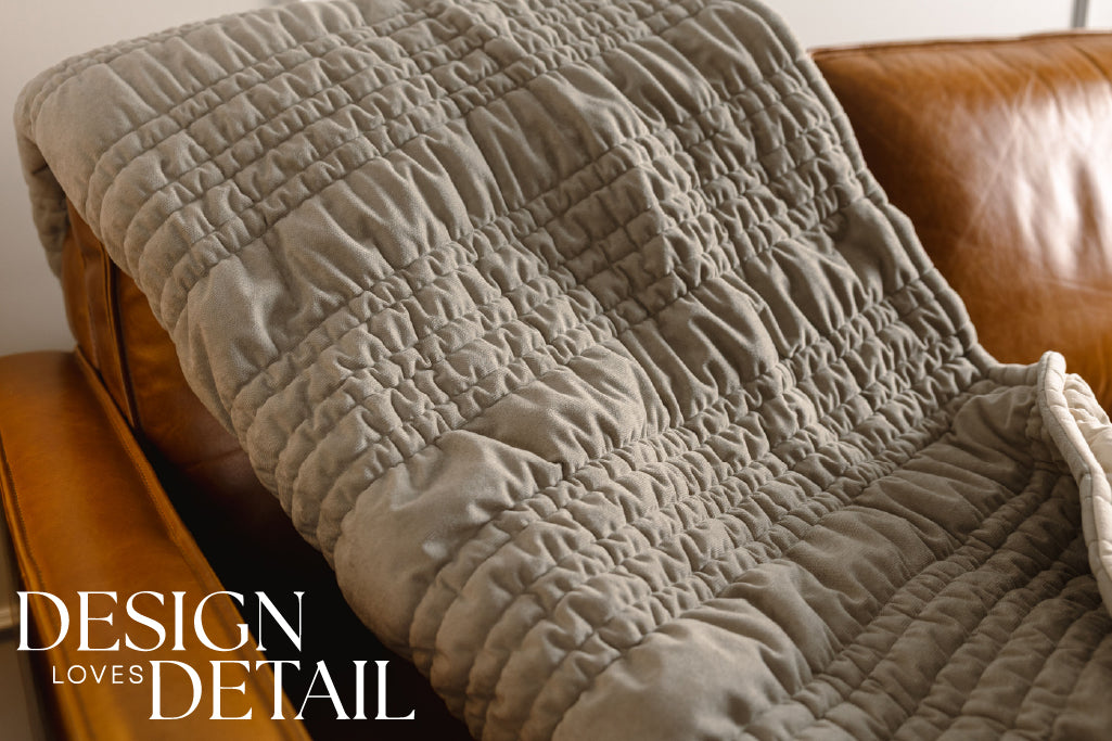  A sage green blanket on an orange leather couch.