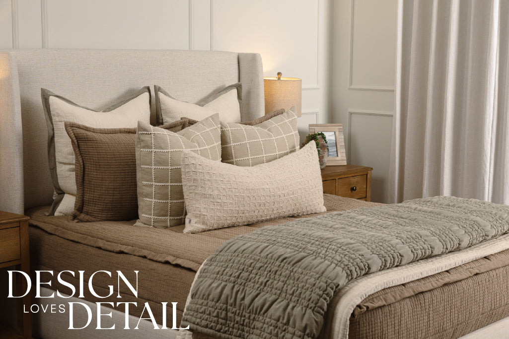 Tan woven quilted bedding with cream and green accessories. 