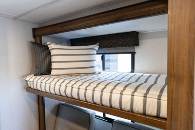 A twin RV bunk bed made with striped black and white zipper bedding.