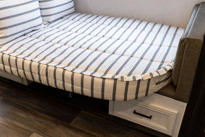 A close up view of a rounded RV corner bed made with striped black and white zipper bedding.
