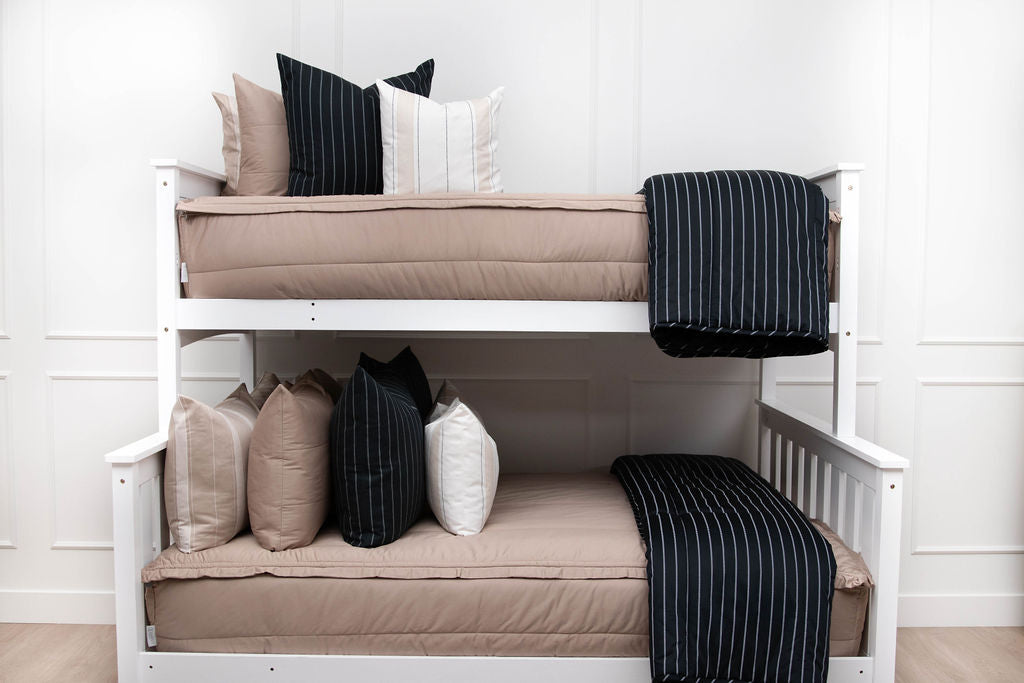A standard bunk bed with both bunks made with tan zipper bedding and neutral and black striped pillows and blankets.