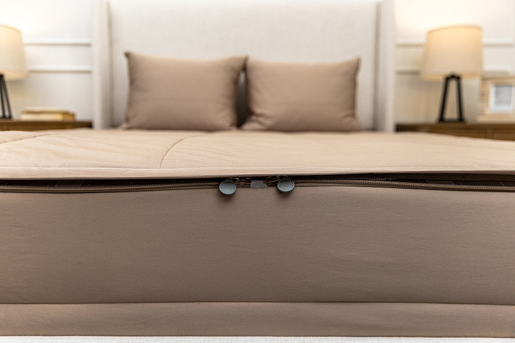 End of bed showing double zippers on tan zipper bedding.