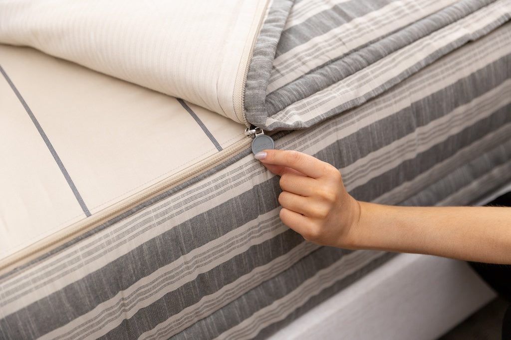 Close up photo of zipper being pulled on classic neutral stripe zipper bedding.