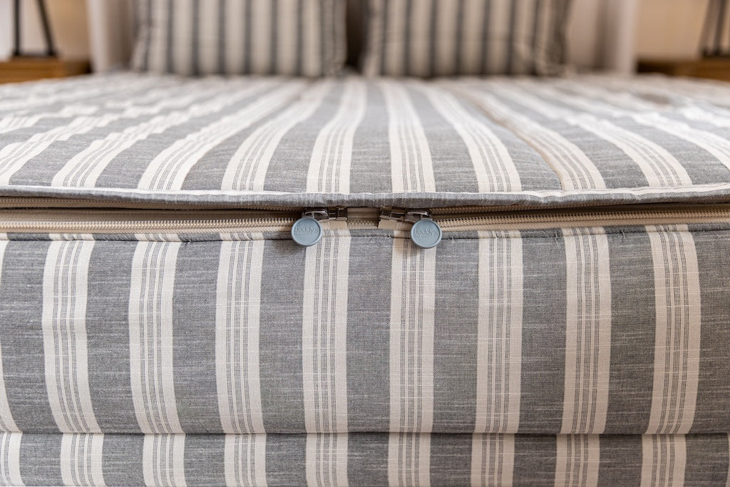 End of bed showing double zippers on neutral stripe zipper bedding.