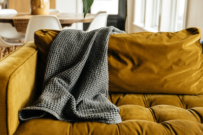 Gray textured throw blanket draped on couch. 