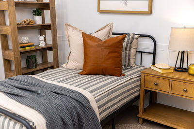 Twin bed with neutral stripe zipper bedding with tan, gray and rustic accessories.