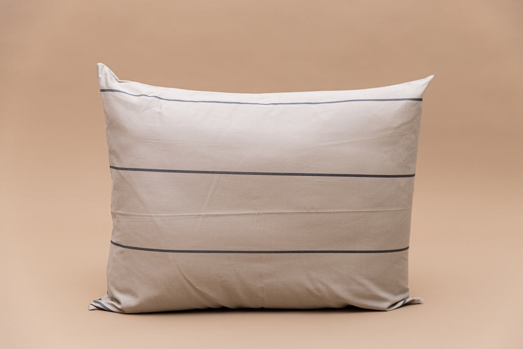A cream and gray striped pillowcase on a tan background. 