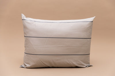 A cream and gray striped pillowcase on a tan background. 