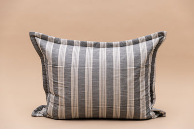 A gray and cream striped pillow sham on a tan background.