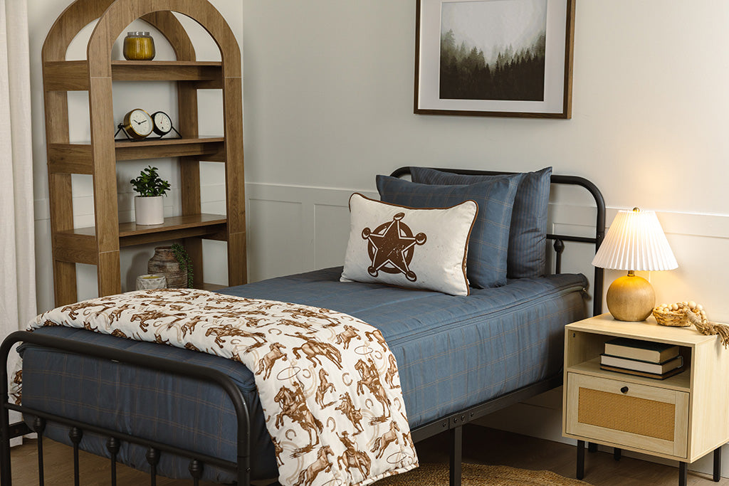 Children zipper bedding in a bedroom on a black bed frame that has a slate blue grid print, with white and brown western accessories.