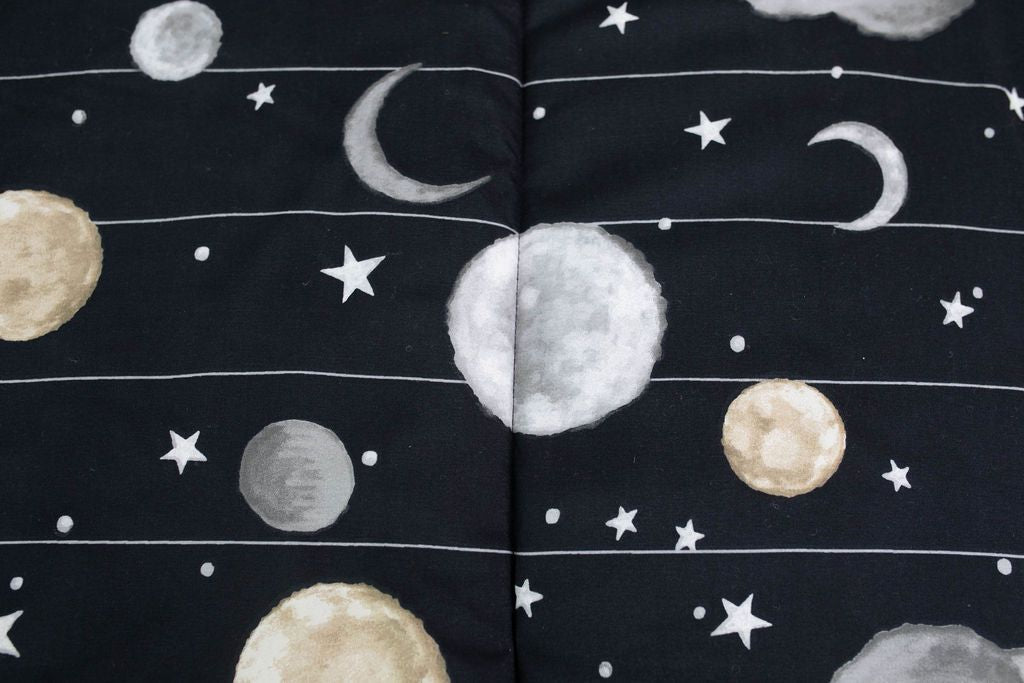 A close up of the print on a set of black planets and stars kids zipper bedding.
