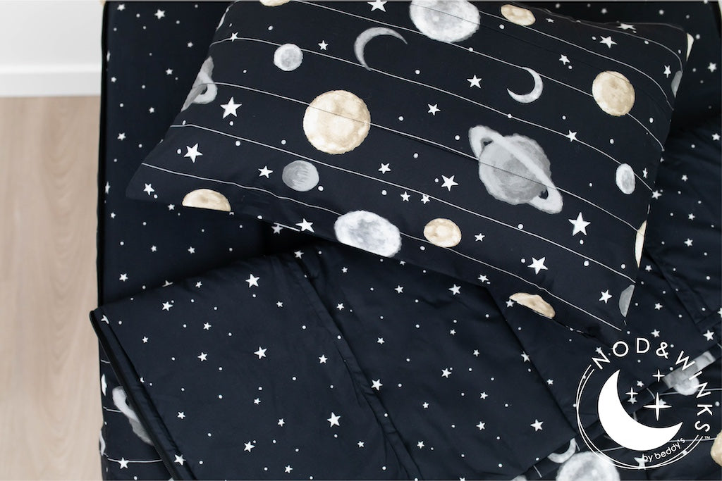 A twin bed made with black plants and stars kids zipper bedding, the top unzipped and slightly pulled back and a pillow on the bed.