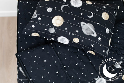 A twin bed made with black plants and stars kids zipper bedding, the top unzipped and slightly pulled back and a pillow on the bed.