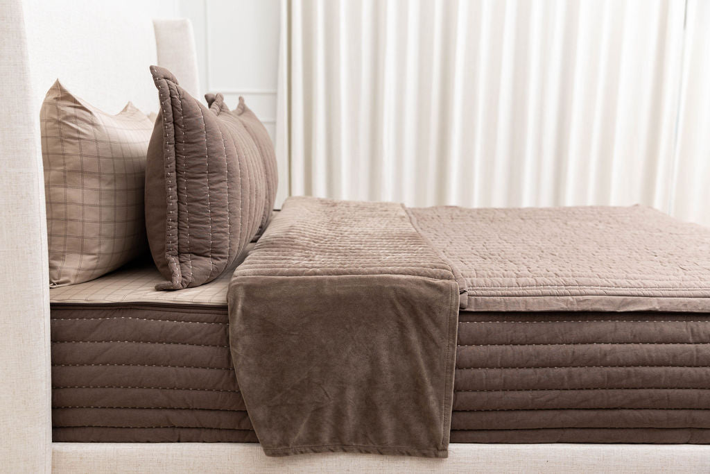 A bed made with brown zipper with the top pulled back to reveal the inner lining