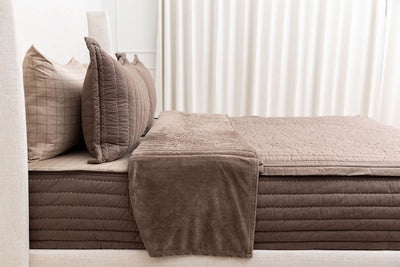 A bed made with brown zipper with the top pulled back to reveal the inner lining