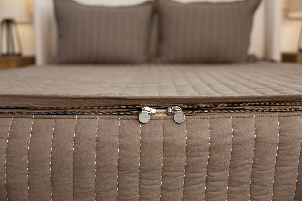 End of bed showing double zippers on brown stitched zipper bedding.