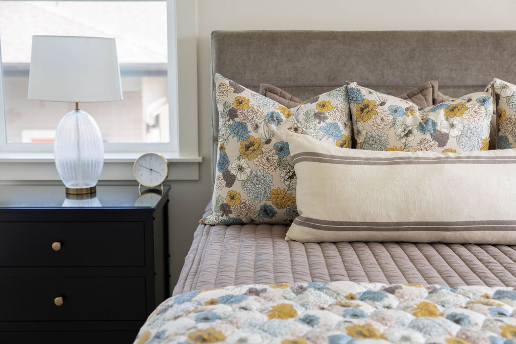 A bed made with brown zipper bedding and blue and yellow floral bedding accessories