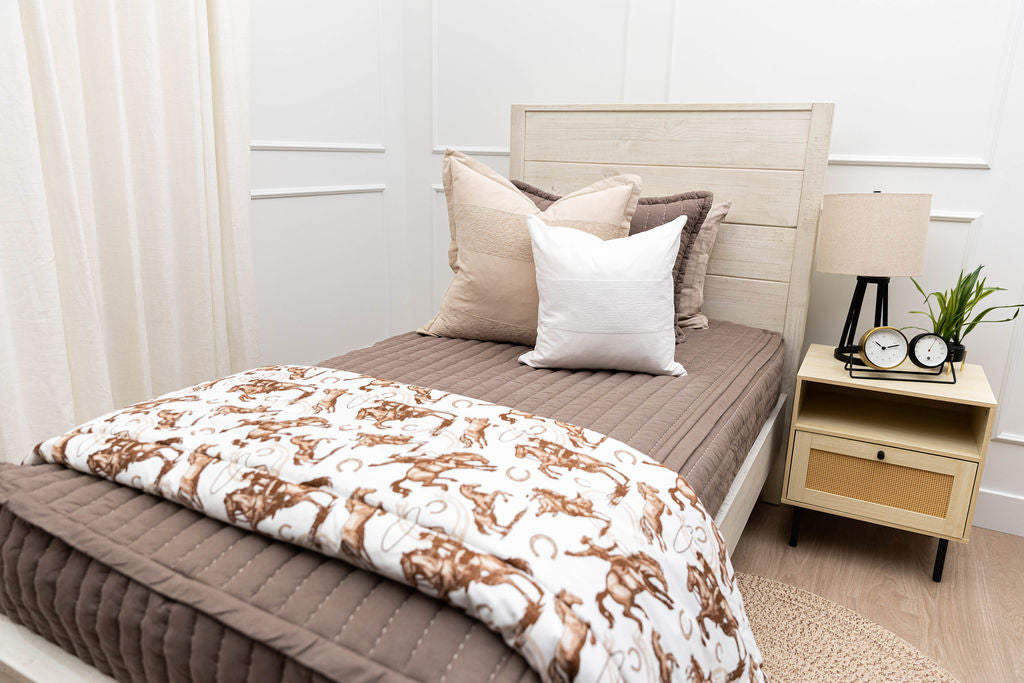 A twin bed made with brown zipper bedding and western theme throw blanket