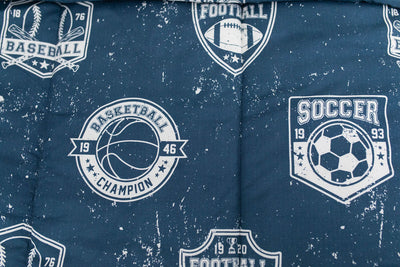 A close up on the print of a set of blue sports themed kids zipper bedding