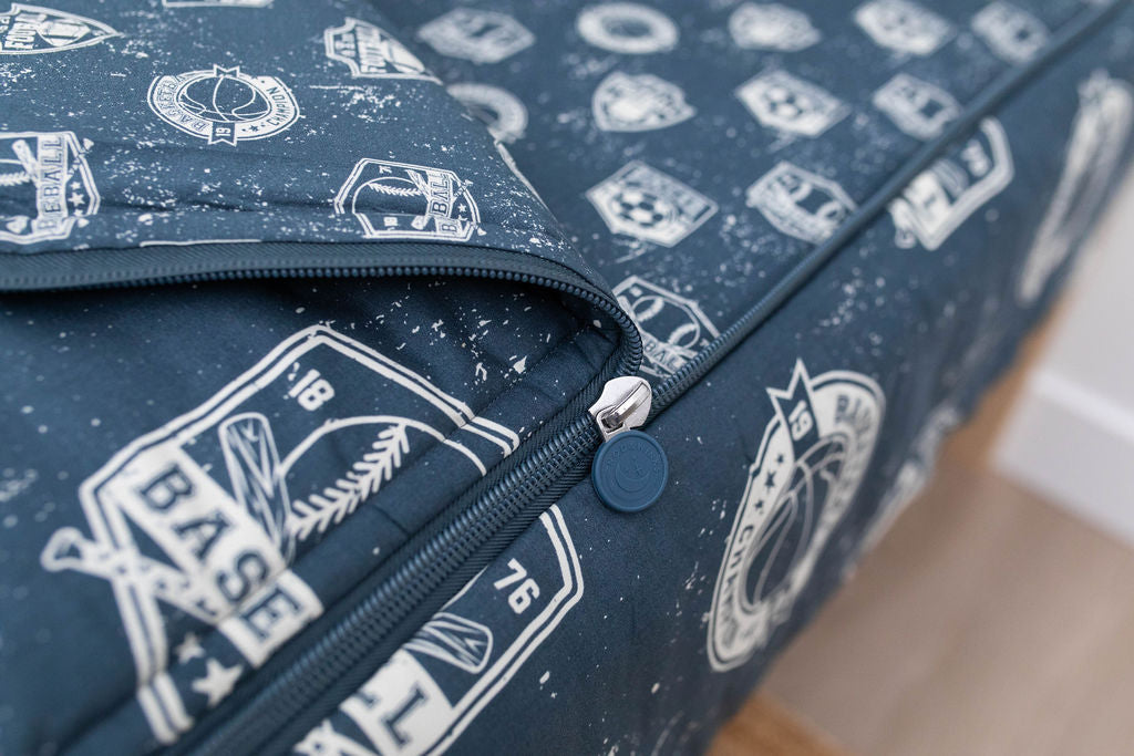 A closeup on the zipper feature of a set of blue sports themed kids zipper bedding