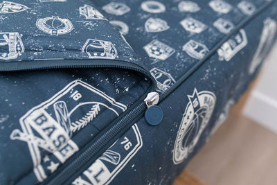 A closeup on the zipper feature of a set of blue sports themed kids zipper bedding