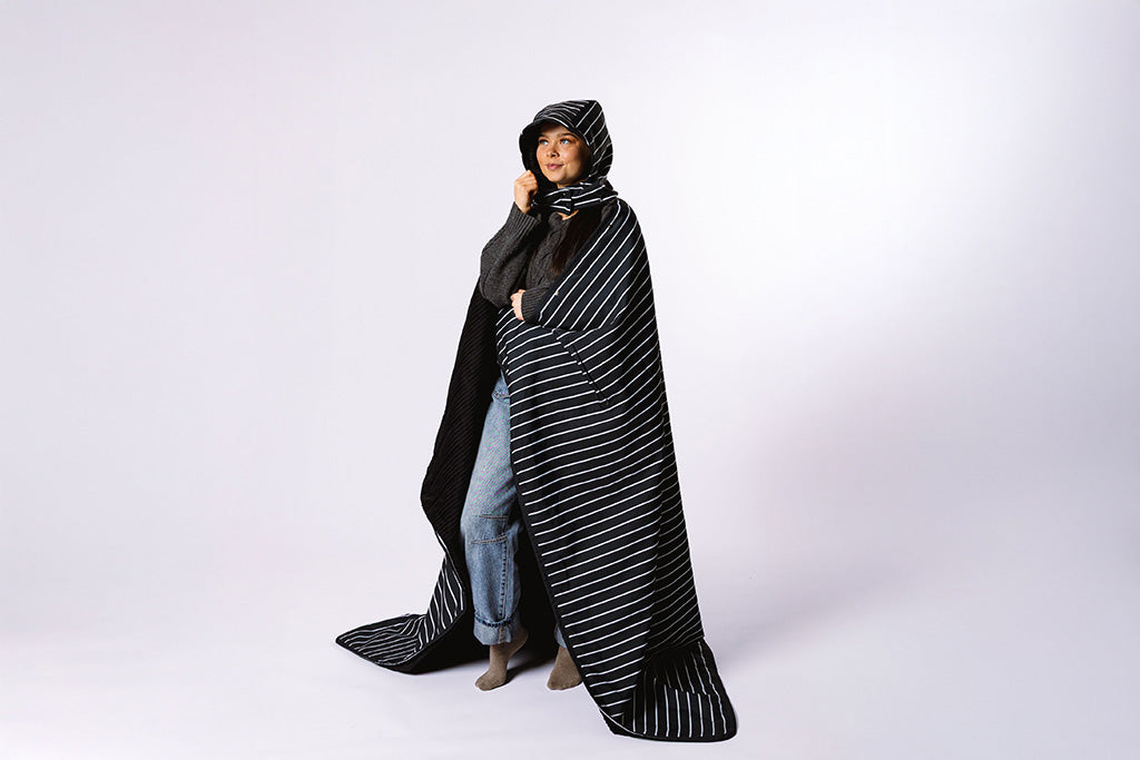 Woman wrapped in the beddy's stadium blanket on a white background.. 