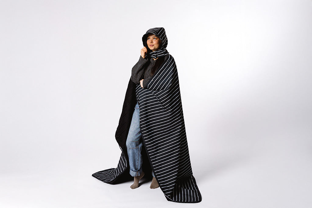 Woman wrapped in the beddy's stadium blanket on a white background.. 
