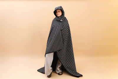 Woman wrapped in the beddy's stadium blanket on a tan background.. 