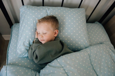 little boy sleeping in light blue zipper bedding with airplane design
