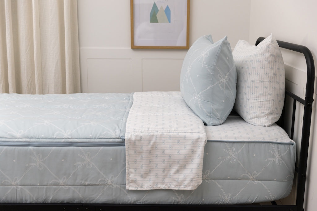 A bed made with bows printed zipper bedding, showcasing the pillowcase and sham and the top of the bedding turned down to show the inside lining.