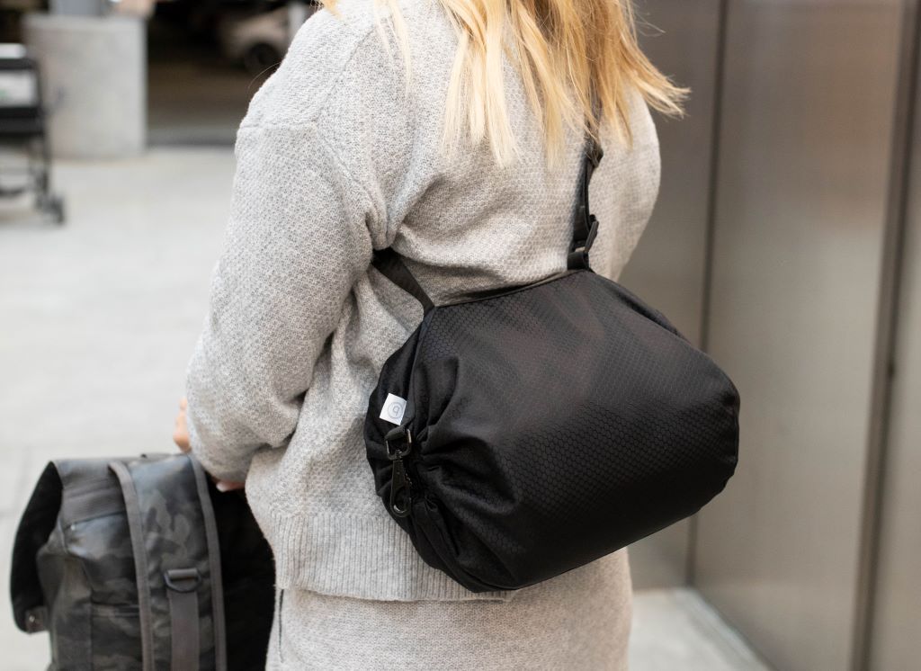 A person with their luggage walking in an airport and a close up view of a black rounded bag strapped to them. 