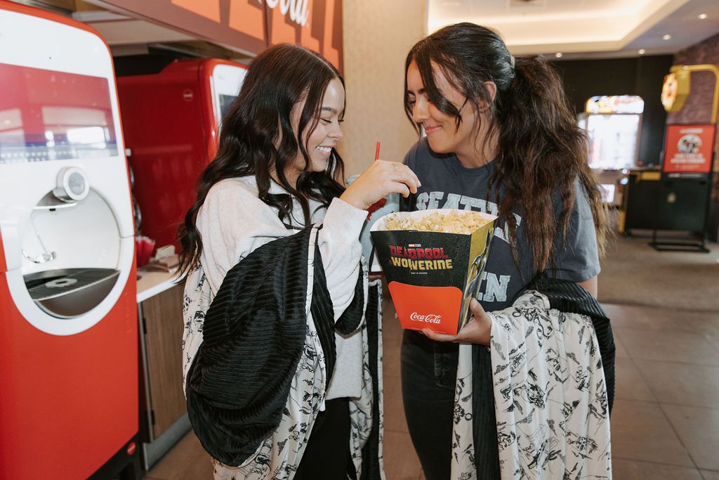 Two people at the movies holding popcorn and holding black and white western theme pattern blankets. 