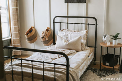 A twin bed made with light tan cars kids zipper bedding and adorned with neutral pillows and blankets. 