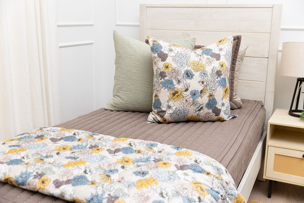 A twi n bed made with brown zipper bedding and blue and yellow floral bedding accessories