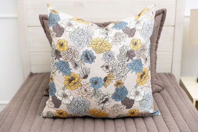 A bed made with brown zipper bedding with a blue and yellow euro sham on top