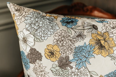 A close up corner view of a multicolor floral euro patterned pillow arranged on a white background.