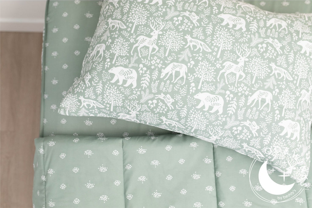 A twin bed made with sage green woodland creatures and trees kids zipper bedding, the top unzipped and slightly pulled back and a pillow on the bed.