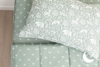 A twin bed made with sage green woodland creatures and trees kids zipper bedding, the top unzipped and slightly pulled back and a pillow on the bed.