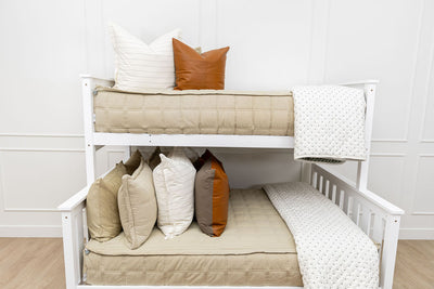 A bunk bed where both bunks are made with green zipper bedding and an assortment of cream and leather bedding accessories.