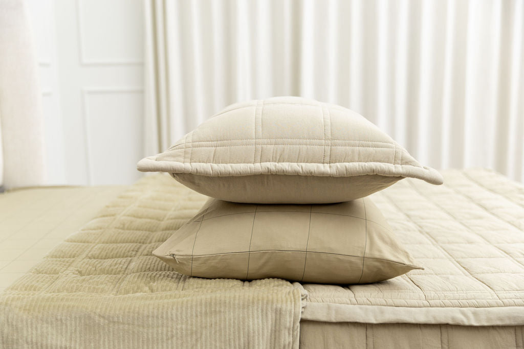 A khaki grid pattern pillowcase and matching sham on a made bed with khaki quilted zipper bedding. 