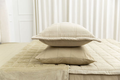 A khaki grid pattern pillowcase and matching sham on a made bed with khaki quilted zipper bedding. 