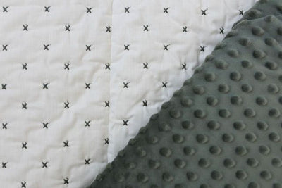 A dual sided blanket, one side with minky and the other side cream with gray x pattern stitching