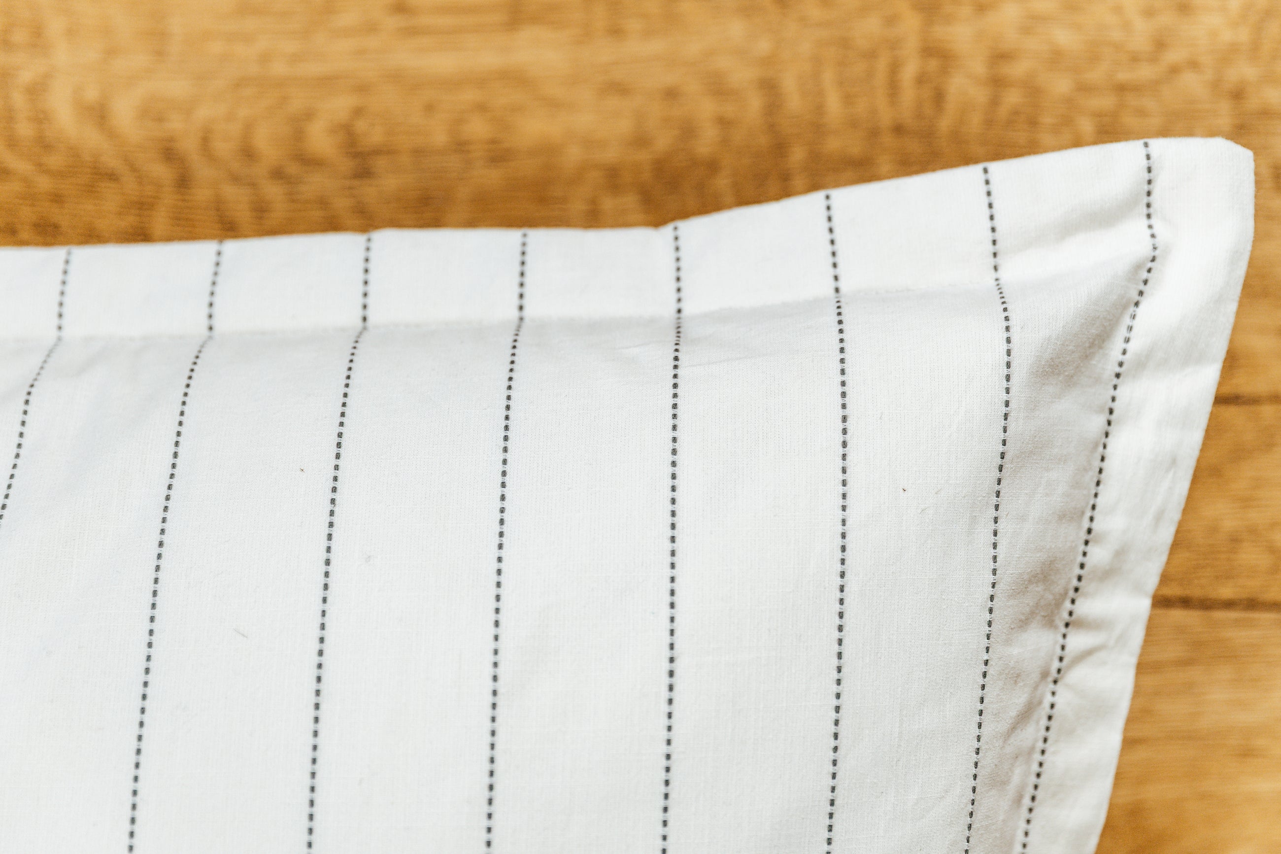 A close up corner view of a cream XL euro pillow with green stripes.