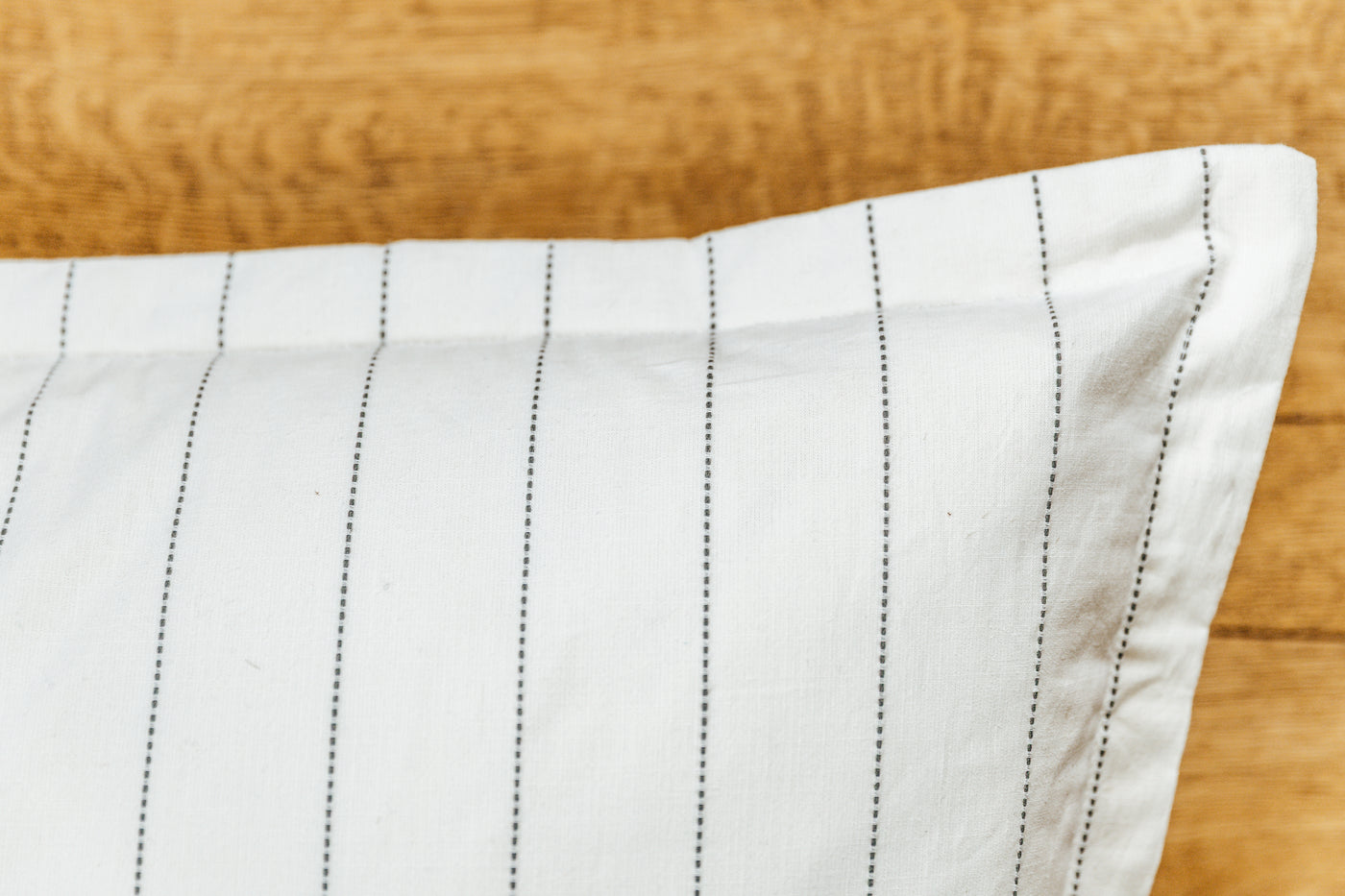 A close up corner view of a cream XL euro pillow with green stripes.