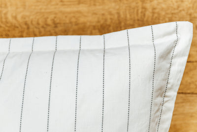 A close up corner view of a cream XL euro pillow with green stripes.