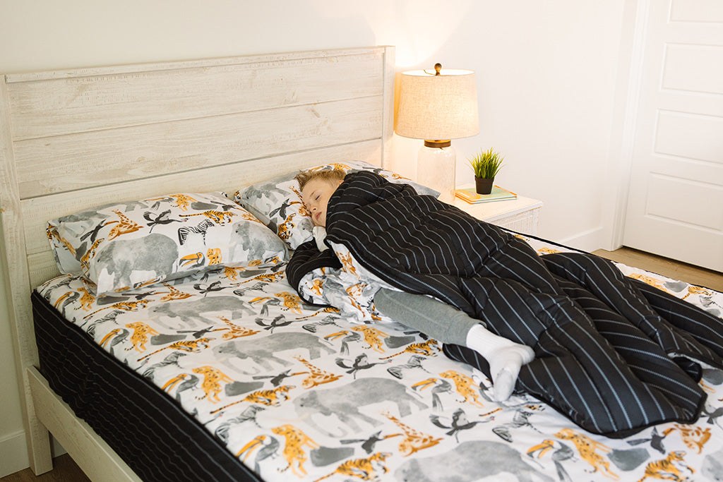 A young boy sleeping in jungle print zipper bedding. 
