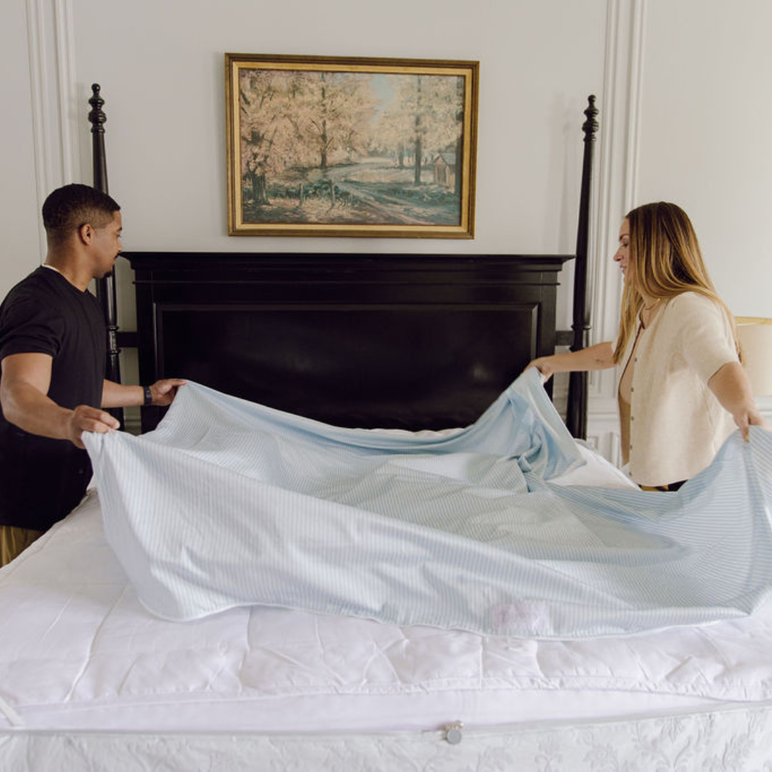 A couple arranging the detachable ZipBase fitted sheet top on their Beddy's set.